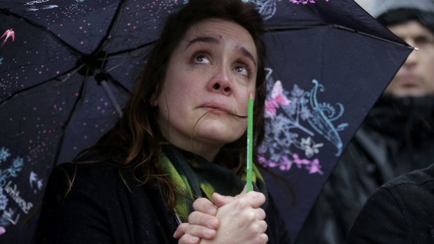 A woman holding a pencil cries in front of the Notre Dame Cathedral in Paris during a minute of silence for victims of the Paris shooting.