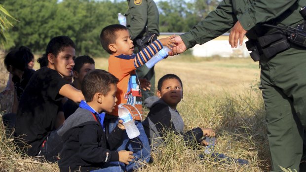 Border Patrol agents pass out water as they process a group of 22 undocumented migrants caught  in Texas in June last year.