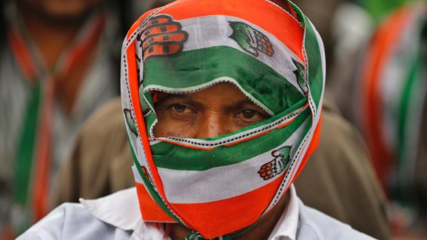 A supporter of India's main opposition Congress party covers himself with party's scarf during an election rally at Dhrangadhra in Gujarat.