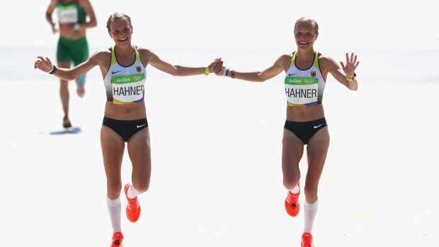 Anna Hahner and her sister Lisa Hahner hold hands at they approach the finish line during the Women's Marathon.
