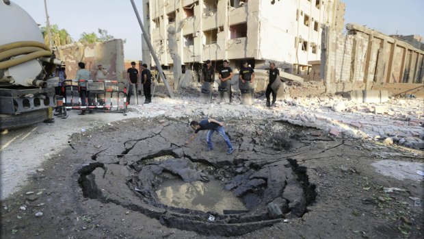 An Egyptian worker checks a hole believed caused by a car bombing outside the national security building on Thursday.