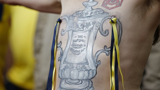 An Arsenal fan shows off the FA Cup trophy painted on his chest.