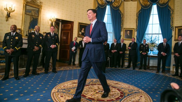 James Comey walks across the room to greet the President after being spotted against the far wall. 