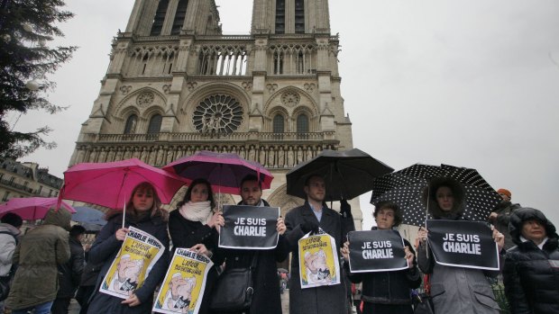 People hold signs reading 'Je suis Charlie' as they stand in front of Notre-Dame Cathedral.