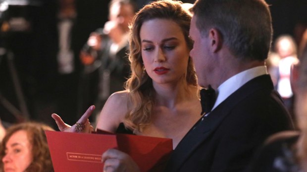 Brie Larson being handed the best actor envelope by accountant Brian Cullinan backstage at the Oscars.