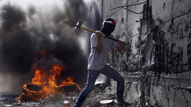 A Palestinian student tries to break the separation barrier between the West Bank and Israel during a protest this week.