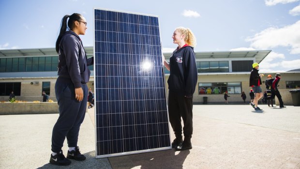 Amaroo year 10 students Savannah Sithideth and Taylah Rattey with one of the solar panels to be installed at the school.