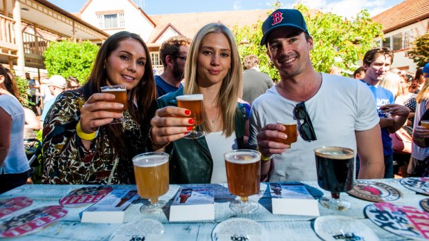 Canberran Lindsey Anders, left, with her friends Hannah Fane and James Small from Sydney, enjoy a drink from Feral Brewing Co at the festival on Saturday. 
