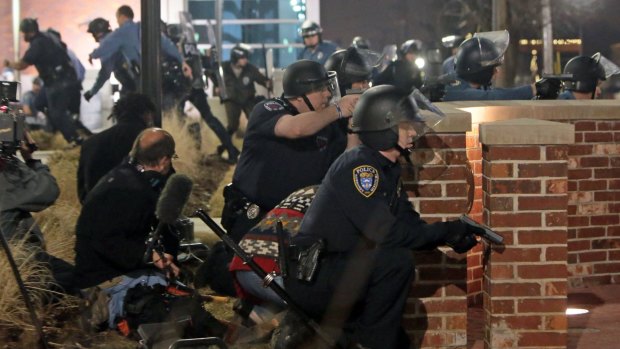 Police take cover after two officers were shot while standing guard in front of the Ferguson Police Station.