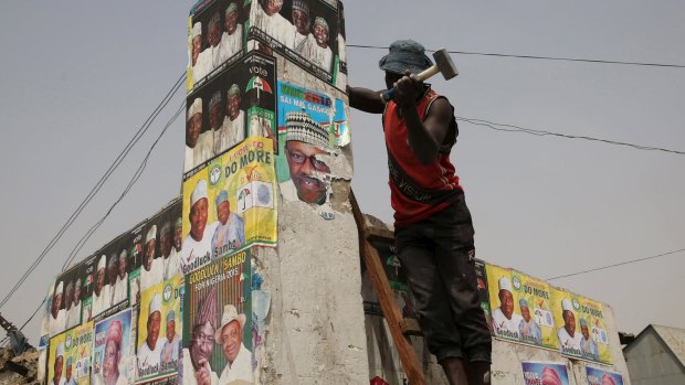 Candidates use fight against extremists to their advantage: A man works on a wall with elections posters at a market in Kano.
