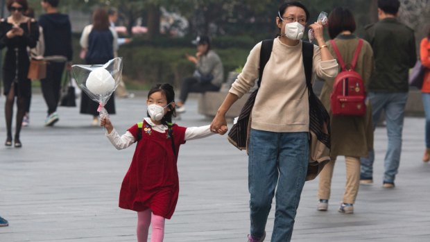 A woman and child wear masks during a hazy day in Beijing. 