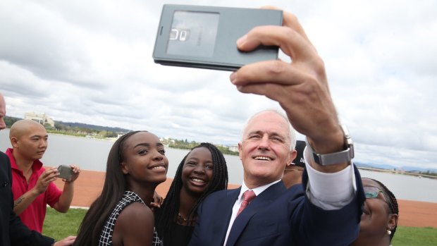 Prime Minister Malcolm Turnbull takes a selfie with new Australian citizens Lydia Banda-Mukuka and Chilandu Kalobi Chilaika after the citizenship ceremony on Australia Day in Canberra.