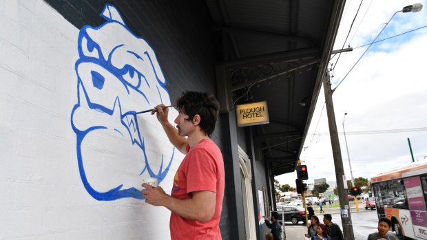 Kyle Weyburne paints a bulldog on the side of the Plough Hotel in Footscray.