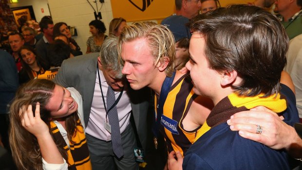 Family affair: Lachie Langford joins brother Will and father Chris in the rooms after the Hawks’ premiership win. 