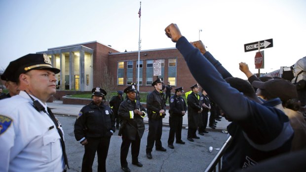 Marchers raise their fists in front of Baltimore police guarding the department's Western District police station during a march for Freddie Gray in Baltimore.