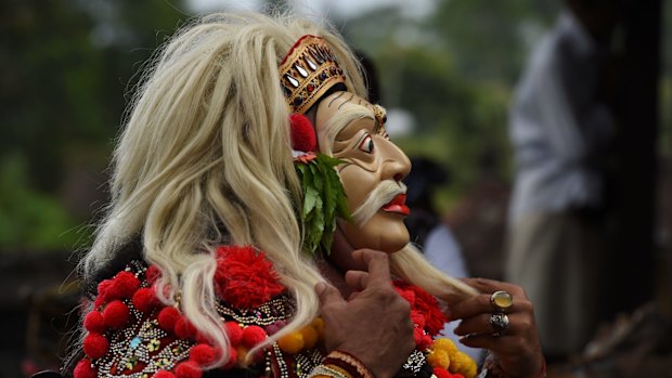 A Balinese Bondres, a comedian wearing a mask, entertains people during Purnama Kapat, the full moon ceremony at the Besakih Mother Temple inside the 9km danger zone near Mount Agung.