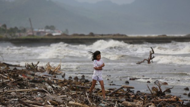 A girl walks along the shore as strong waves from Typhoon Hagupit hit Atimonan in the eastern Philippines.