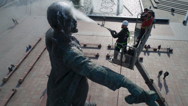 A worker uses a water sprayer to wash a statue of Lenin ahead of the centenary.