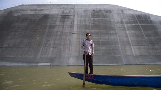 Ota Khami, 55, stands on a boat over where his home was before it was bulldozed to make way for the Sesan 2 dam. 