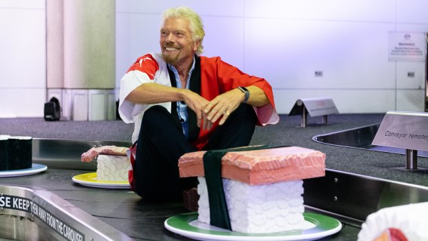 Sir Richard Branson rides the 'giant sushi train' Brisbane Airport during a media event announcing Brisbane to Haneda flights.