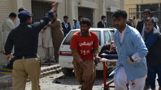 Pakistani volunteers rush an injured person to get medical help after the bomb blast in Quetta.