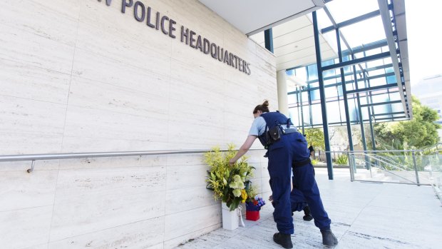 A police officer lays flowers at in tribute to Curtis Cheng, who worked for the police finance department.