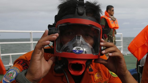 Current: A diver prepares his mask during a search operation for the missing plane.