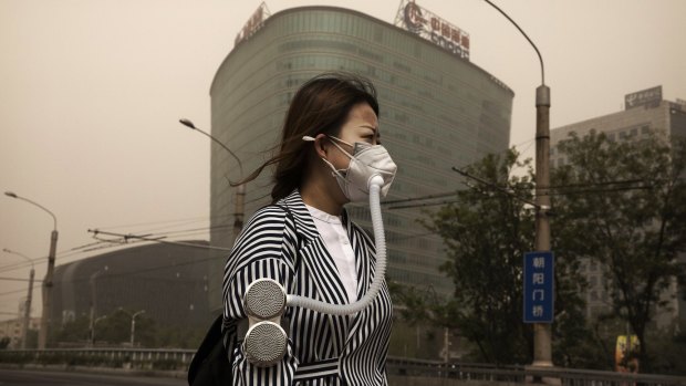 A woman wears a mask to protect from particles blown in during the sandstorm.