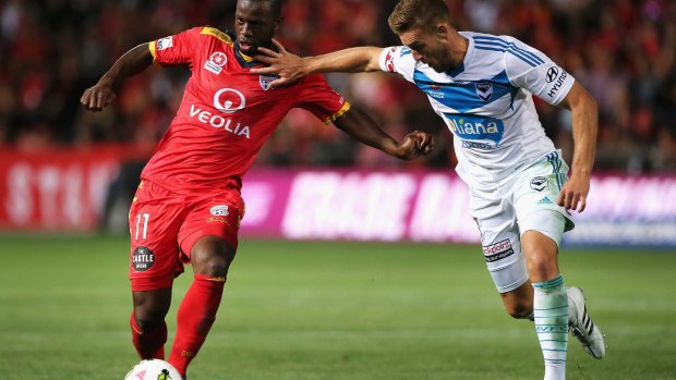 Bruce Djite (left) of Adelaide United competes for the ball with Nicholas Ansell of the Victory.