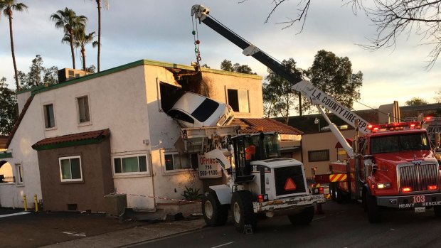 Fire officials use a crane to pull the vehicle out of the building and bring it down.