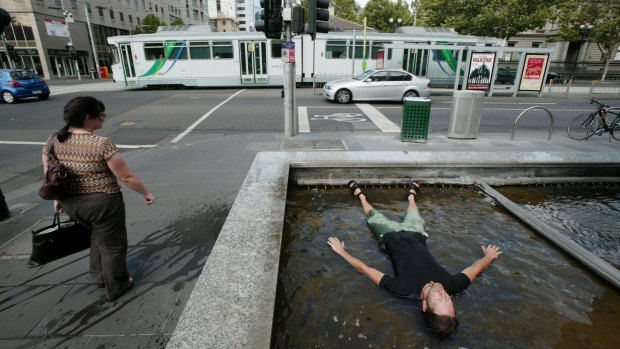 A man dives into a fountain on Wednesday as a heatwave takes hold of Melbourne.