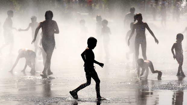Children cool off under a fountain in Madrid in July this year.