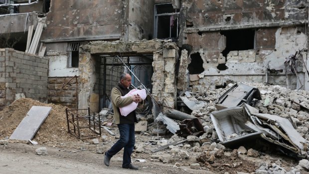 A man with a baby in a bombed-out area of Aleppo, Syria, in January.