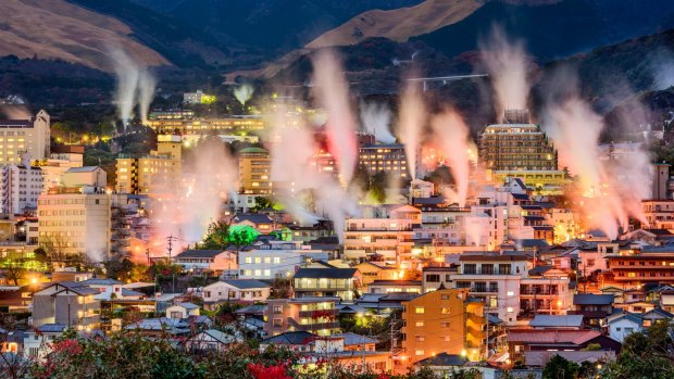 Hot spring bath houses with rising steam in Beppu, Japan.