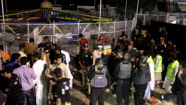 Pakistani police officers and rescue workers gather at the site of the bomb explosion in Lahore in Sunday. 