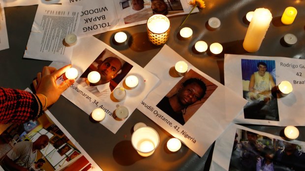 A woman places a candle on top of pictures of the executed prisoners at a vigil in Sydney.