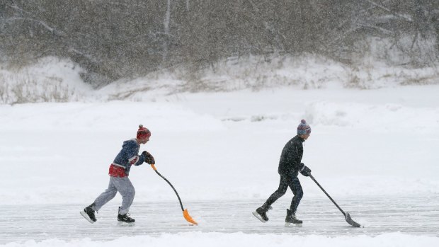 Pond hockey players attempt to shovel snow faster than it can fall in Yarmouth, Maine. 