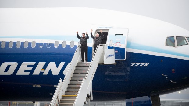 Boeing pilots wave while exiting the 777X plane after landing.