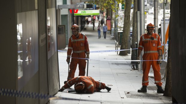 Police and SES search for a mobile phone along Collins Street on Friday. 