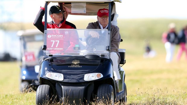 US presidential contender Donald Trump (right) drives a golf buggy on the first day of the Women's British Open.