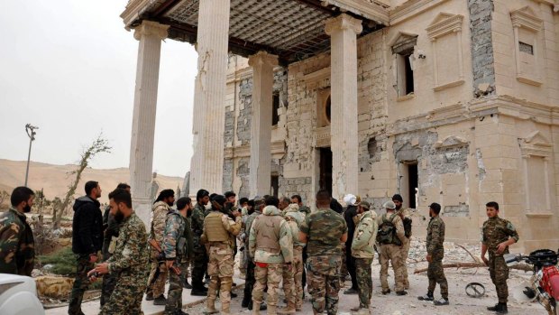 Syrian soldiers outside a damaged palace in Palmyra.