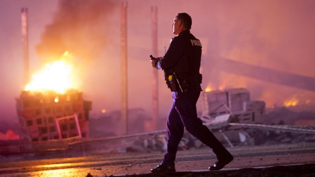 A police officer walks past a blaze after rioters plunged Baltimore into chaos.