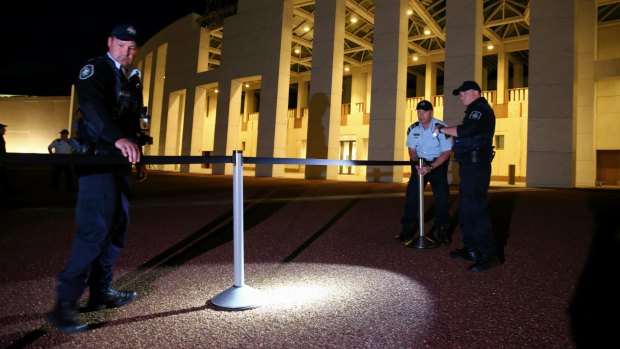 AFP officers set up bollards to cordon off the media on the forecourt of Parliament House.
