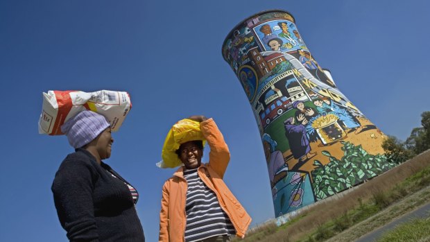 Two women chat in front of Orlando Power Station tower in Soweto, Johannesburg.