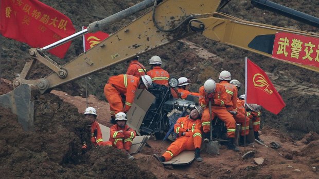Rescuers rest near an excavator digging for survivors following the landslide.