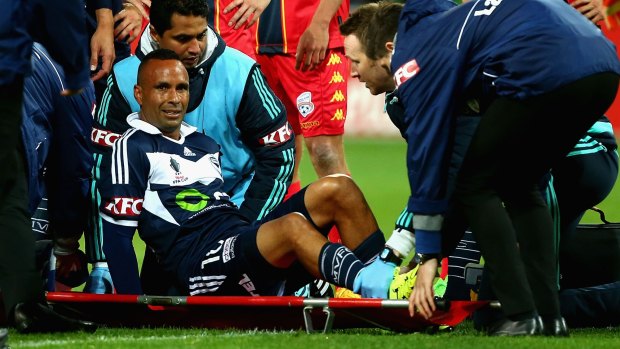 Victory veteran Archie Thompson receives medical attention after being injured in a heavy challenge.