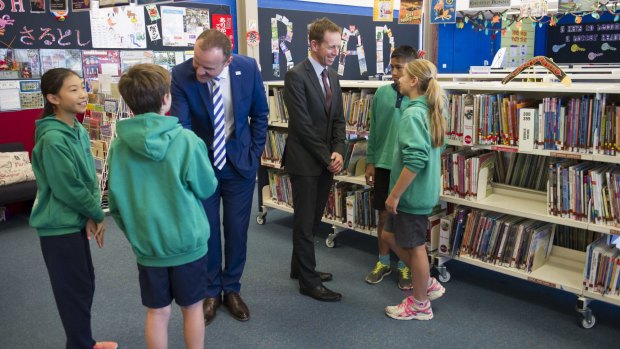  Andrew Barr, left, and Shane Rattenbury meet students at Kaleen Primary on Monday, where they announced plans to phase out paper forms and notes in schools.