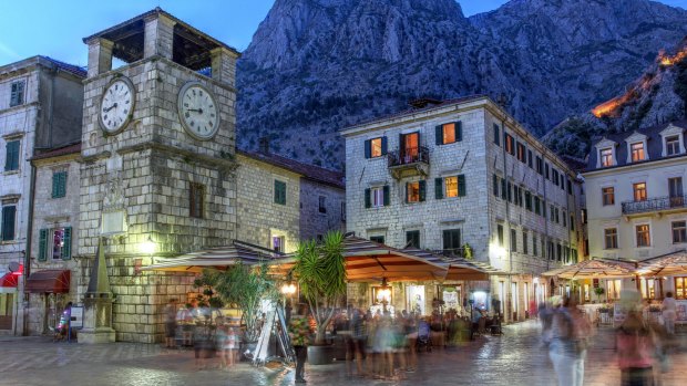 The medieval town of Kotor, Montenegro, at twilight, featuring the Square of Arms and the clock tower near the Maritime entrance gate.