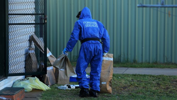 A NSW forensic officer carries evidence bags in the backyard of Vincent Stanford's home on Maiden Avenue in Leeton last week.