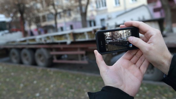 A man takes a photo of a truck carrying part of a wing from Malaysia Airlines flight MH17 in Donetsk, eastern Ukraine.